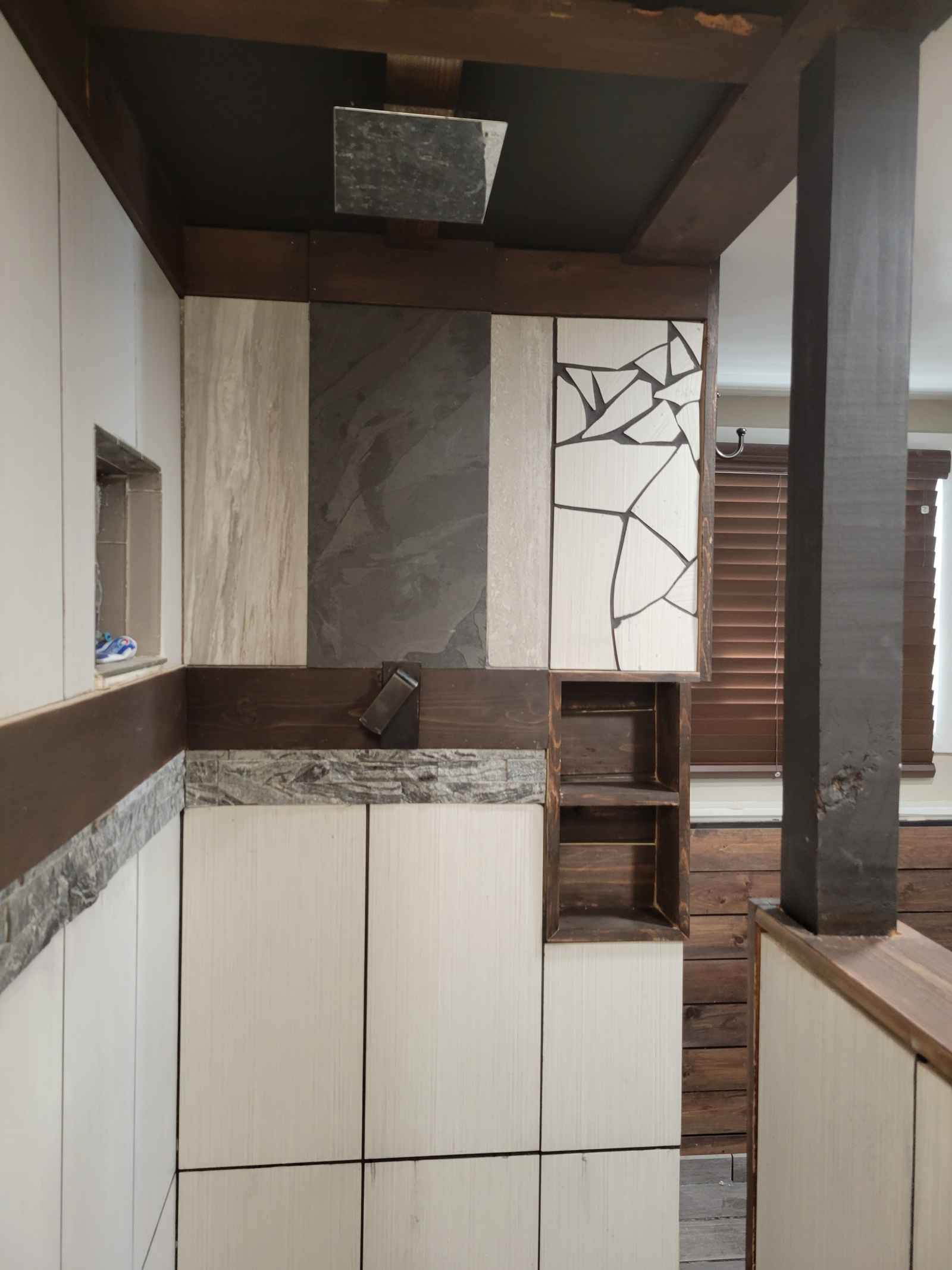 Custom bathroom feature wall under construction mixing slate, travertine, mosaic tile, and wood